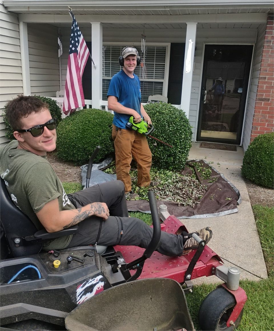 The Root to Roof Relief crew trimming hedges and hauling debris on a job site