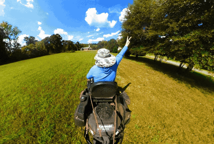 Root to Roof Relief crew member riding a lawn mower across a green field — from your lawn to your roof, we've got you covered